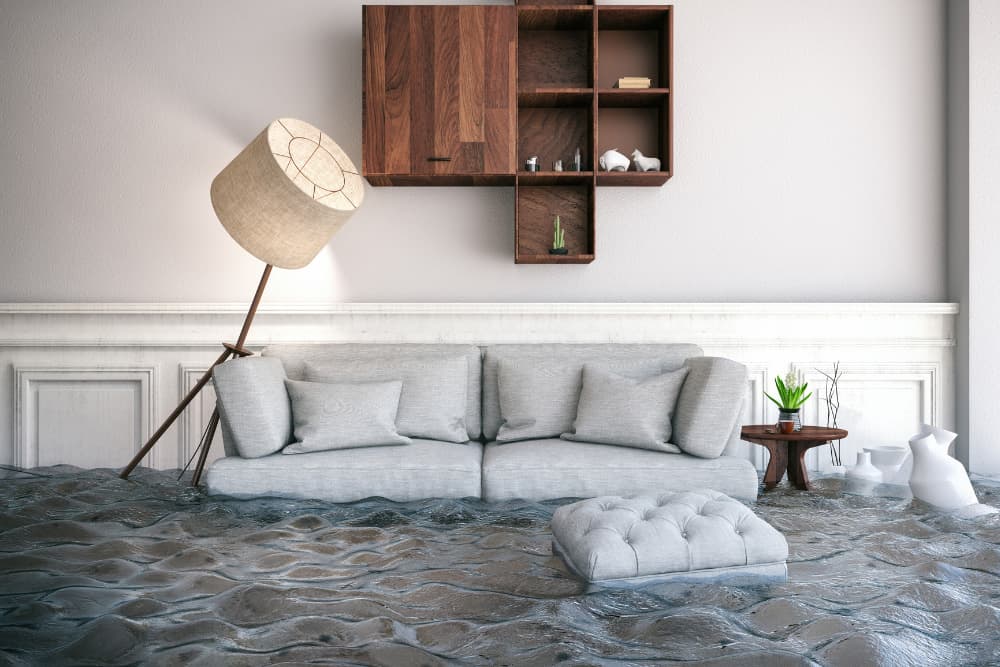 A flooded living room with a sofa floating in need of emergency flood cleanup near Bloomington CA.